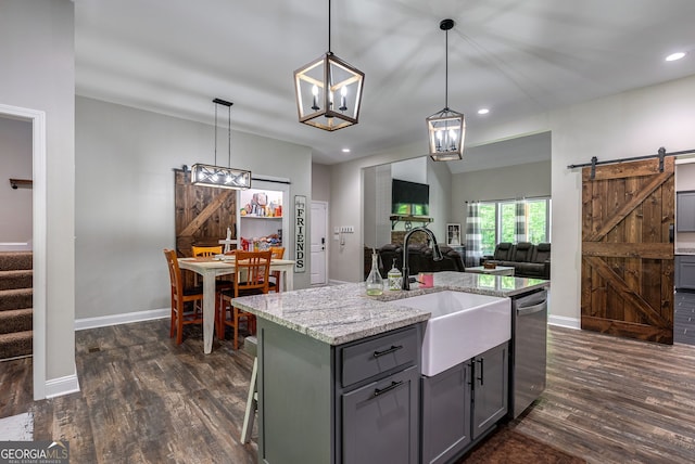 kitchen with dishwasher, a kitchen island with sink, hanging light fixtures, light stone countertops, and a barn door