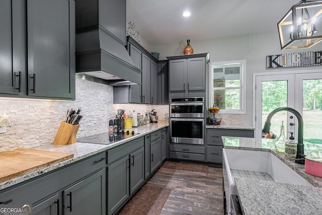 kitchen featuring sink, gray cabinetry, hanging light fixtures, double oven, and backsplash