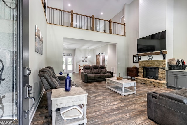 living room featuring dark wood-type flooring, a fireplace, and a high ceiling