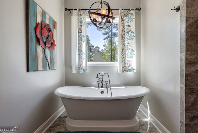 bathroom with a bath and a notable chandelier