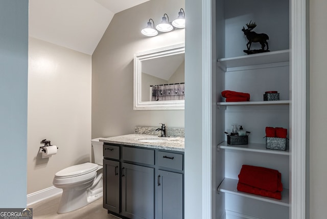 bathroom with vanity, toilet, vaulted ceiling, and built in features