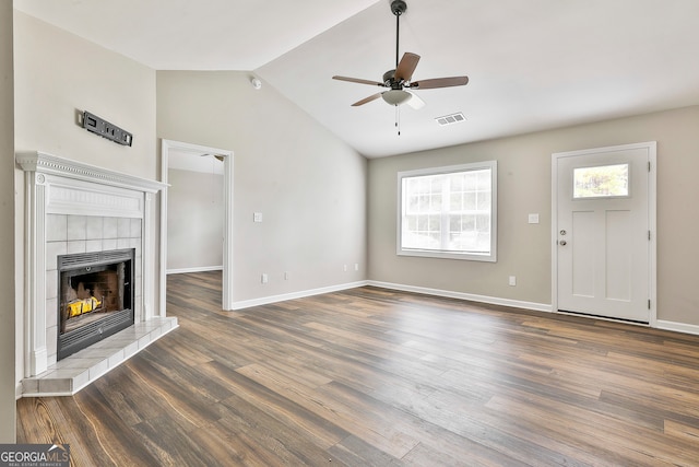 unfurnished living room with dark wood-type flooring, ceiling fan, lofted ceiling, and a tile fireplace