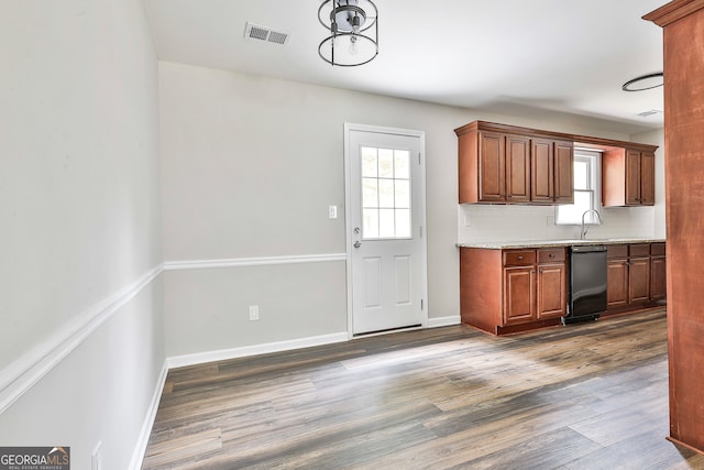 kitchen with dark wood-type flooring, decorative backsplash, light stone counters, and dishwasher