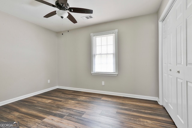 unfurnished bedroom featuring dark hardwood / wood-style floors, a closet, and ceiling fan