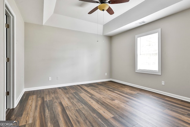 spare room featuring dark wood-type flooring, ceiling fan, and a raised ceiling