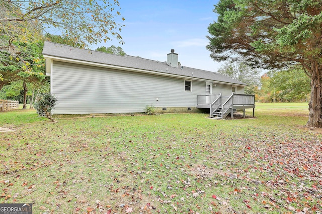 back of property featuring a wooden deck and a lawn