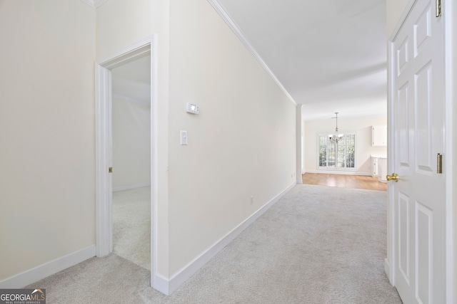 hallway with light carpet, crown molding, and a notable chandelier