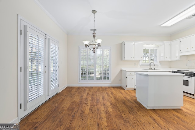 kitchen with white stove, decorative light fixtures, white cabinets, crown molding, and hardwood / wood-style flooring