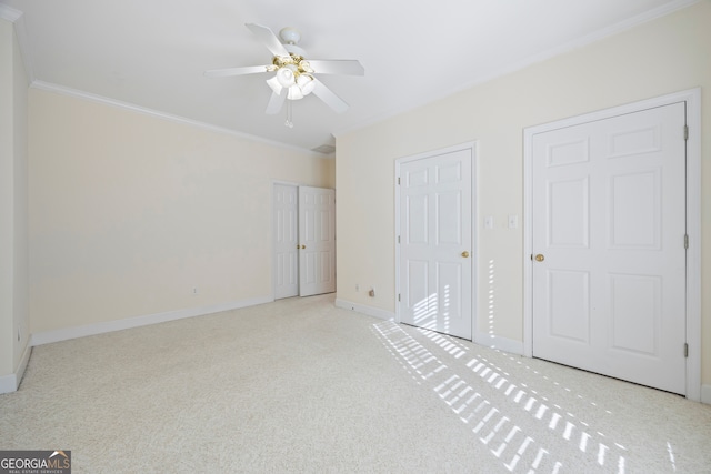 unfurnished bedroom featuring ornamental molding, two closets, light colored carpet, and ceiling fan