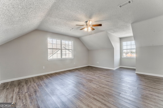 additional living space featuring vaulted ceiling, baseboards, visible vents, a ceiling fan, and wood finished floors