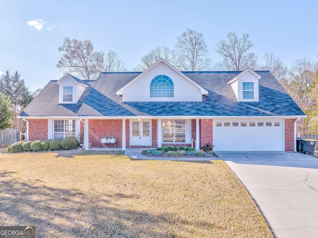 view of front facade featuring driveway, a front yard, roof with shingles, brick siding, and a garage