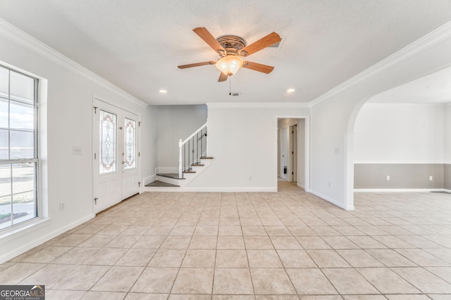 foyer with ceiling fan, stairway, and crown molding