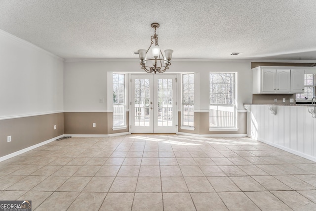 unfurnished dining area with an inviting chandelier, ornamental molding, a textured ceiling, light tile patterned flooring, and visible vents