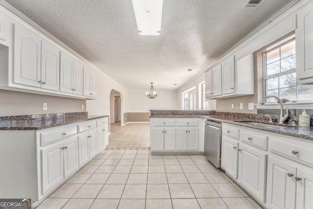 kitchen with light tile patterned flooring, a peninsula, dishwasher, arched walkways, and a sink