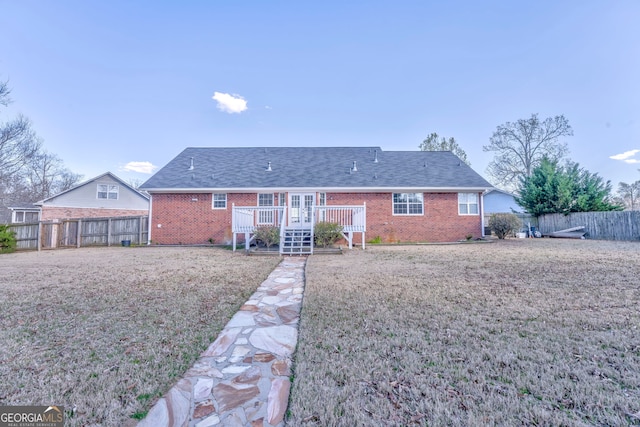 back of house with a lawn, a wooden deck, brick siding, and fence private yard