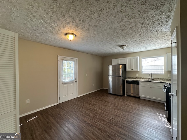 kitchen featuring a wealth of natural light, appliances with stainless steel finishes, dark hardwood / wood-style floors, and white cabinets