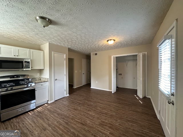 kitchen with stainless steel appliances, light stone countertops, white cabinets, a textured ceiling, and dark hardwood / wood-style flooring