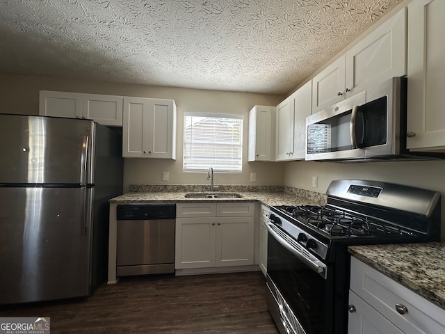 kitchen featuring white cabinets, stainless steel appliances, sink, and light stone counters