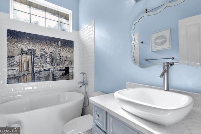 bathroom with toilet, a tub to relax in, and vanity