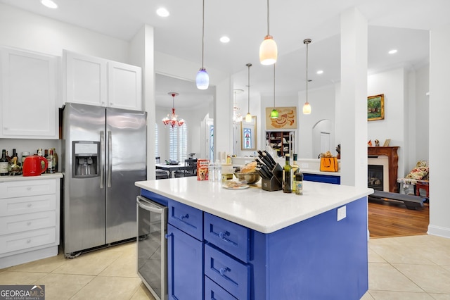 kitchen featuring stainless steel fridge with ice dispenser, pendant lighting, beverage cooler, blue cabinets, and white cabinetry