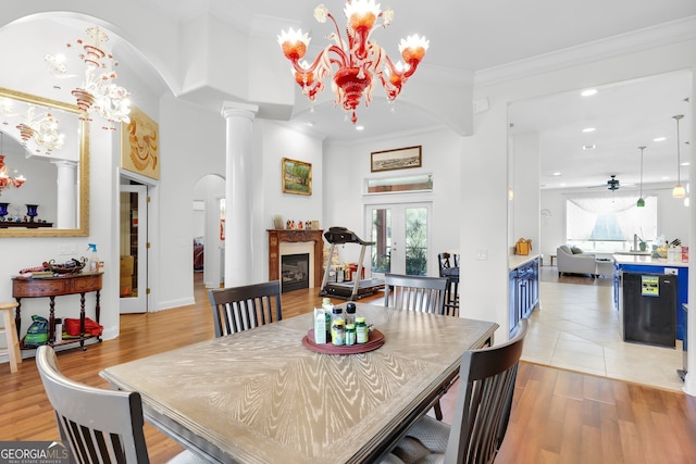 dining room with light hardwood / wood-style flooring, ornamental molding, ceiling fan with notable chandelier, and a wealth of natural light