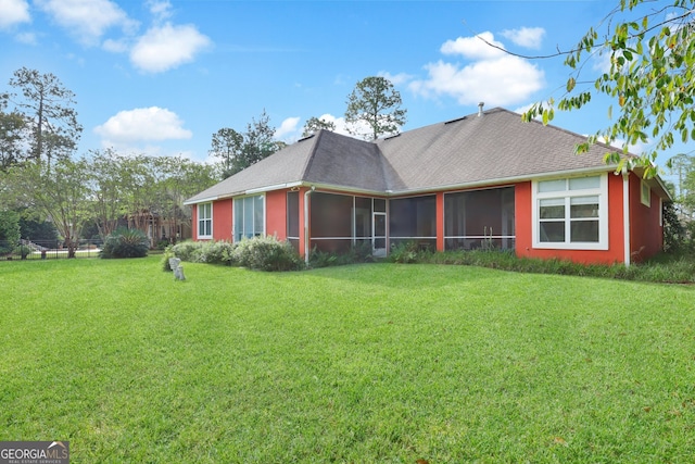 back of house featuring a sunroom and a lawn