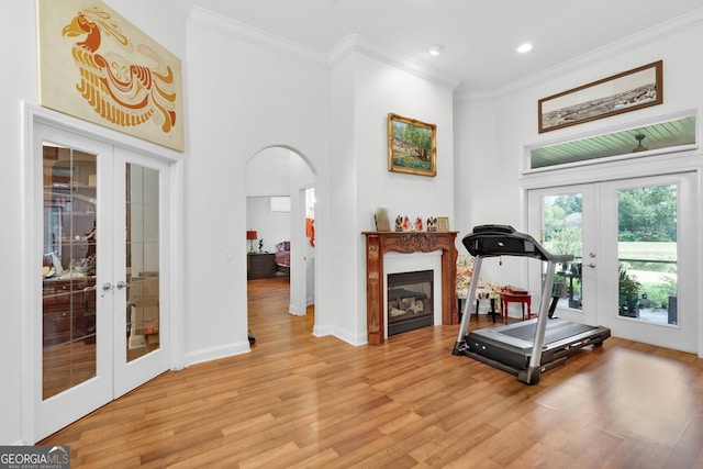 workout room featuring french doors, light hardwood / wood-style floors, and crown molding