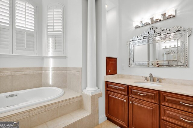 bathroom featuring vanity, a relaxing tiled tub, and tile patterned flooring