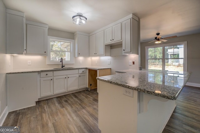 kitchen with white cabinetry, wood-type flooring, sink, ceiling fan, and stone counters