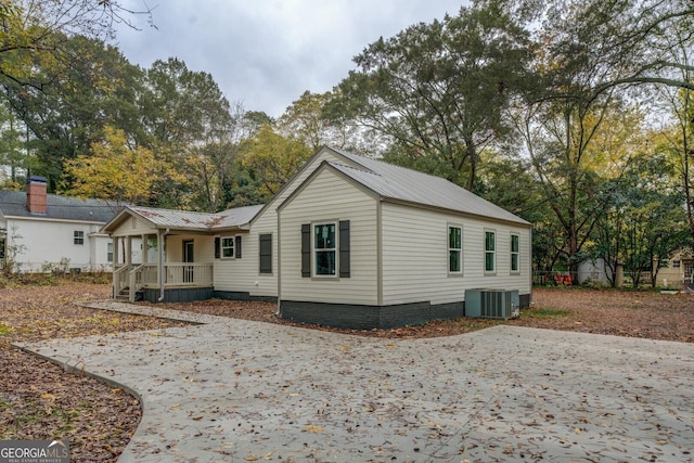 back of house with metal roof and central AC