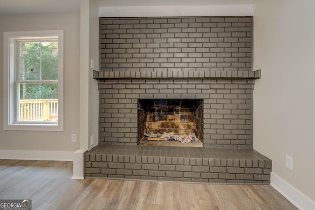 details featuring a brick fireplace, wood finished floors, and baseboards