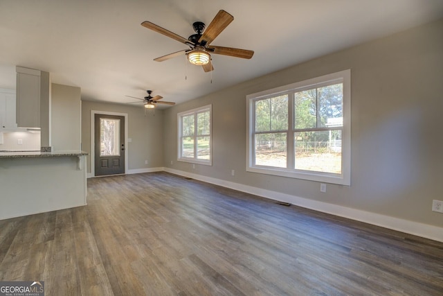 unfurnished living room featuring ceiling fan and dark hardwood / wood-style flooring