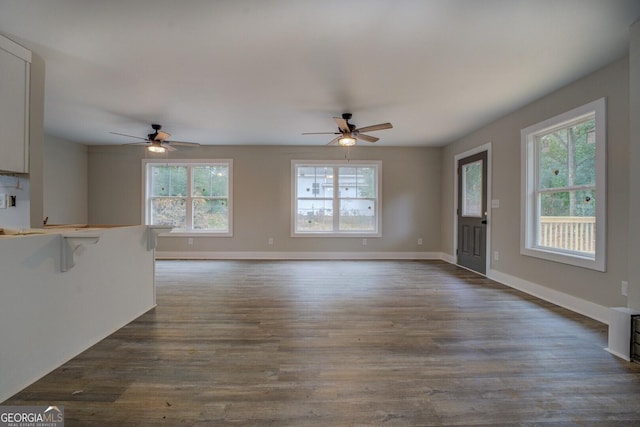 unfurnished living room with ceiling fan, plenty of natural light, and dark hardwood / wood-style floors