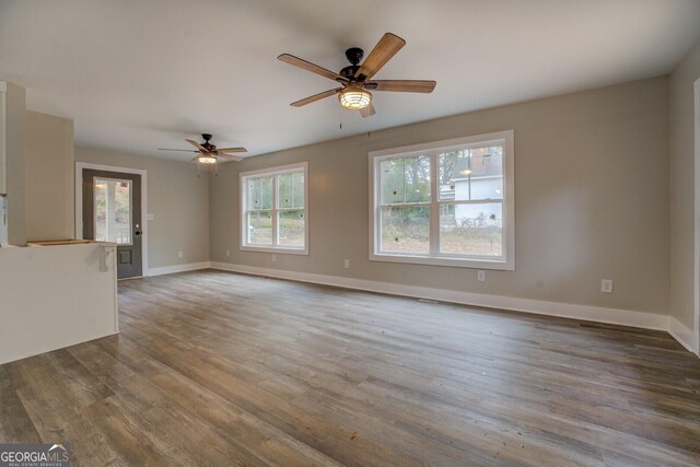 unfurnished living room featuring ceiling fan and dark hardwood / wood-style floors