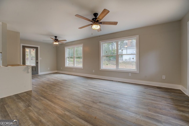 unfurnished living room with ceiling fan, wood finished floors, and baseboards