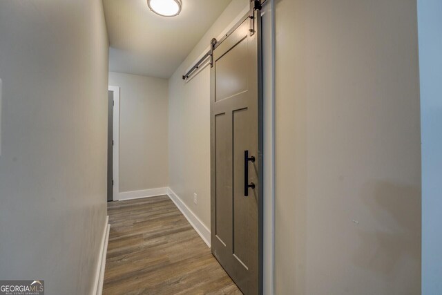 hallway with a barn door and wood-type flooring