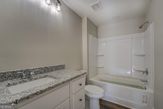 full bath with visible vents, toilet, wood finished floors, vanity, and washtub / shower combination