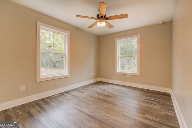 empty room with wood finished floors, a ceiling fan, and baseboards