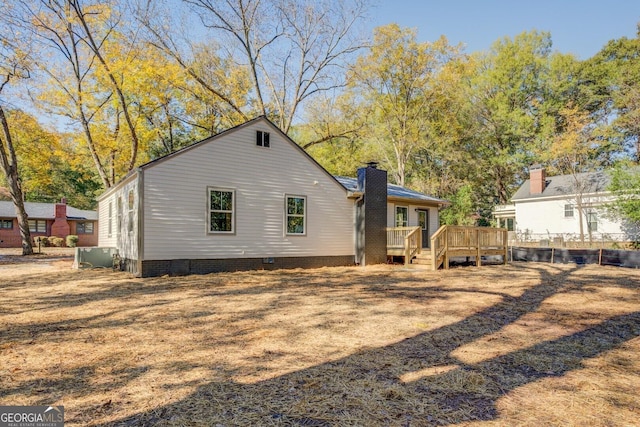 back of house featuring a chimney, crawl space, fence, and a deck