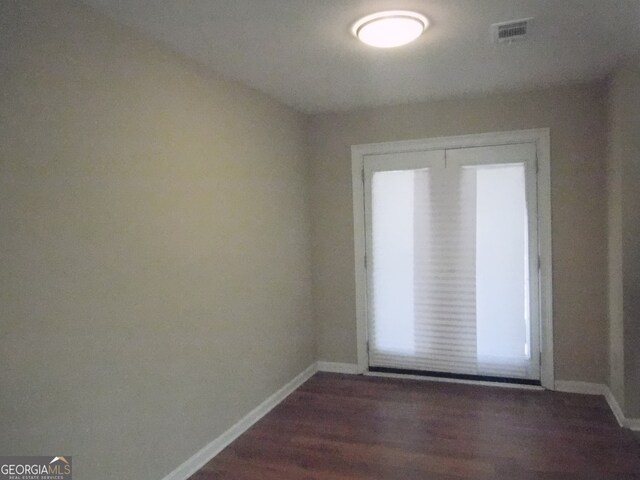 unfurnished room with dark wood-type flooring