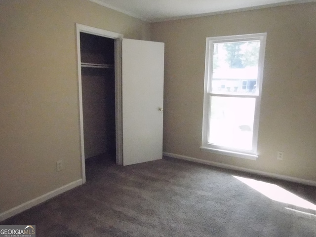 unfurnished bedroom with a closet and dark carpet