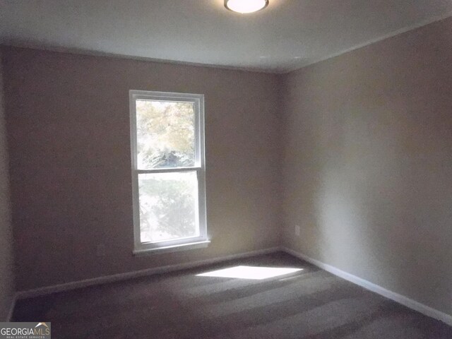 spare room featuring healthy amount of natural light, baseboards, and carpet flooring
