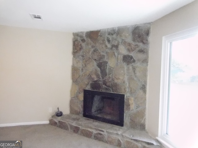 room details with a stone fireplace and carpet floors