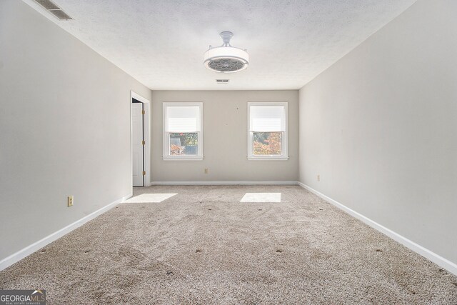 carpeted empty room featuring a textured ceiling