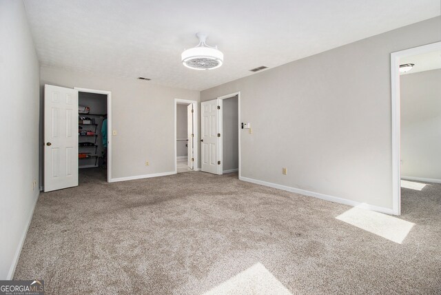 unfurnished bedroom with a walk in closet and carpet floors