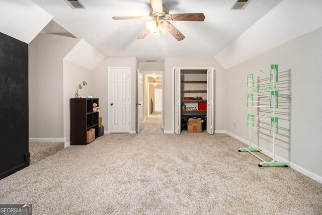 interior space featuring ceiling fan, vaulted ceiling, and light colored carpet