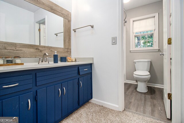 bathroom with toilet, hardwood / wood-style flooring, and vanity