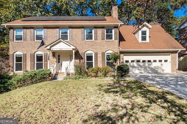 colonial inspired home featuring a front lawn and a garage