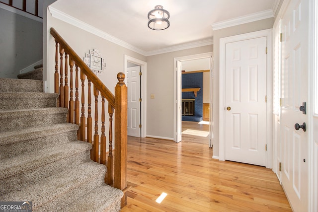 foyer entrance with crown molding, hardwood / wood-style flooring, and a brick fireplace