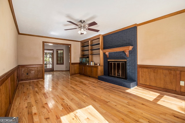 unfurnished living room featuring a fireplace, ornamental molding, light wood-type flooring, and ceiling fan